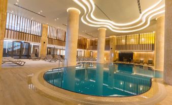 a large indoor swimming pool surrounded by lounge chairs , with several people enjoying their time in the pool at Radisson Blu Hotel Trabzon