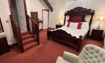 a cozy bedroom with a large bed , red carpet , and a staircase leading to a second floor at The Stanley Arms