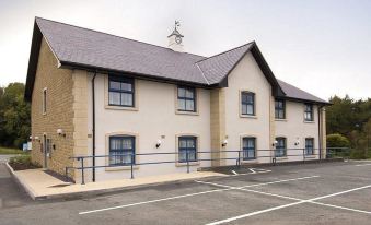 a two - story building with a black roof and white walls is shown next to a parking lot at Premier Inn Bangor (Gwynedd, North Wales)
