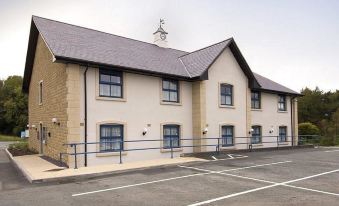 a modern building with white walls , blue trim , and large windows , located next to a parking lot at Premier Inn Bangor (Gwynedd, North Wales)