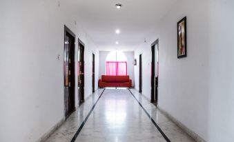 a long , narrow hallway with a red couch in the middle and white walls on both sides at Hotel Rain International, Arrah