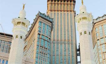 There is a large building with two towers and a tall clock tower in the middle at Emaar Grand Hotel