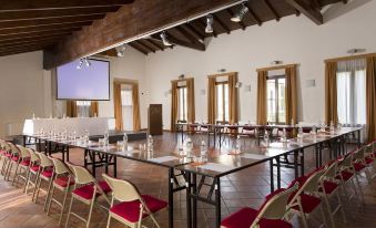 a conference room with tables and chairs set up for a meeting , and a projector screen on the wall at Maranello Palace Hotel