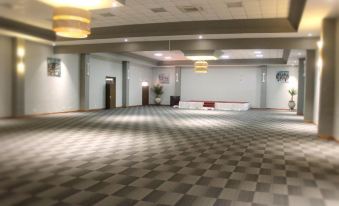 an empty , well - lit room with a checkered floor and several pendants hanging from the ceiling at Grand Palace Hotel Mzuzu