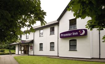 "a white building with a purple sign that says "" premier inn "" on the front , surrounded by trees and grass" at Premier Inn Cardiff East