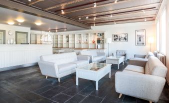 a modern , spacious living room with white sofas and chairs arranged around a coffee table at Fosshotel Eastfjords