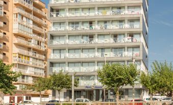 a beachfront hotel with multiple floors , surrounded by trees and cars on the street at Pierre & Vacances Blanes Playa