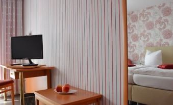 a hotel room with a desk , bed , and television , as well as a striped wallpaper on the wall at Hoffmann