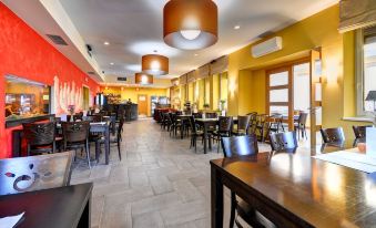 a large restaurant with multiple dining tables and chairs , as well as several potted plants on the table at Hotel Helios