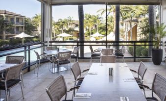 an outdoor dining area with a large glass wall , allowing natural light to fill the space at Mercure Gold Coast Resort