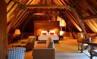 a cozy bedroom with a wooden ceiling , a comfortable bed , and a couch in the corner at Chateau de Bagnols
