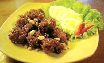 a plate of food on a dining table , consisting of fried meat and vegetables , accompanied by lettuce at Rainbow Resort