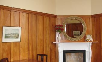 a dining room with a wooden table and chairs , a fireplace , and a mirror on the wall at Left Bank
