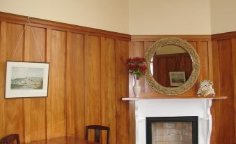 a cozy living room with wooden walls , a fireplace , and a dining table surrounded by chairs at Left Bank