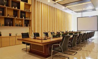 a large conference room with a wooden table , chairs , and a projector screen , surrounded by bookshelves at BBC Hotel Lampung Bandar Jaya