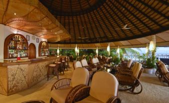 a spacious lounge area with various seating options , including chairs and couches , under a thatched roof at Angaga Island Resort & Spa
