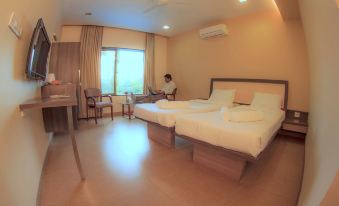 a hotel room with two beds , a desk , and a window , all set up in a well - lit environment at Green Valley Resort