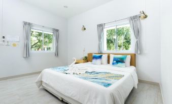 a white bedroom with a large bed , multiple pillows , and a window overlooking a garden at Pimtara Beach Resort