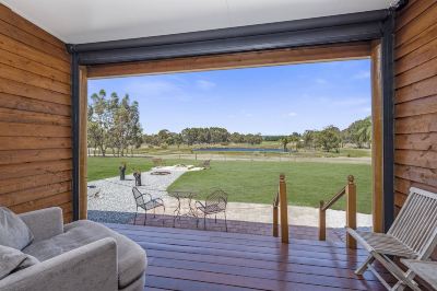 a wooden deck with a couch and chairs overlooking a grassy field , creating a relaxing atmosphere at The Swan Valley Retreat