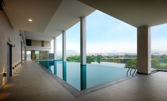 a large indoor swimming pool surrounded by glass walls , with a view of the city skyline in the background at Kip Hotel