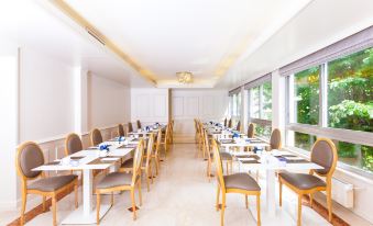a long dining room with white tables and chairs arranged for a group of people at Hotel Geneva by Fassbind