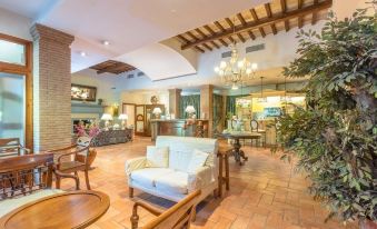 a spacious hotel lobby with a large chandelier hanging from the ceiling , surrounded by wooden furniture and potted plants at Hotel Ristorante la Pergola