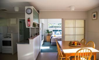 a kitchen with a dining table and chairs , as well as a living room with a couch and a television at Hahei Beach Resort