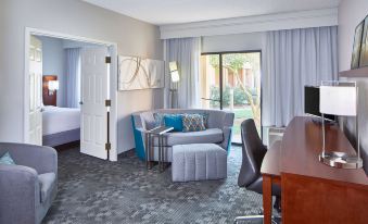 a modern living room with a gray couch , blue cushions , and a tv on the wall at Sonesta Select Raleigh Durham Airport Morrisville