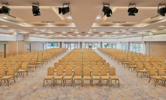 a large , empty conference room with rows of gold chairs and two levels of lights on the ceiling at Le Meridien Lav Split