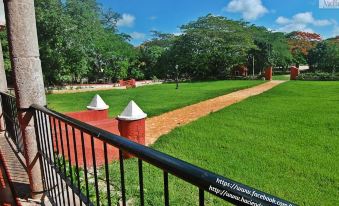 a red fence with a black railing overlooks a grassy area and trees in the background at Hacienda San Miguel Yucatan