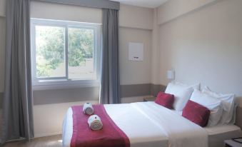 a bed with a white and red blanket is in a room with a window at Work Hotel São Leopoldo