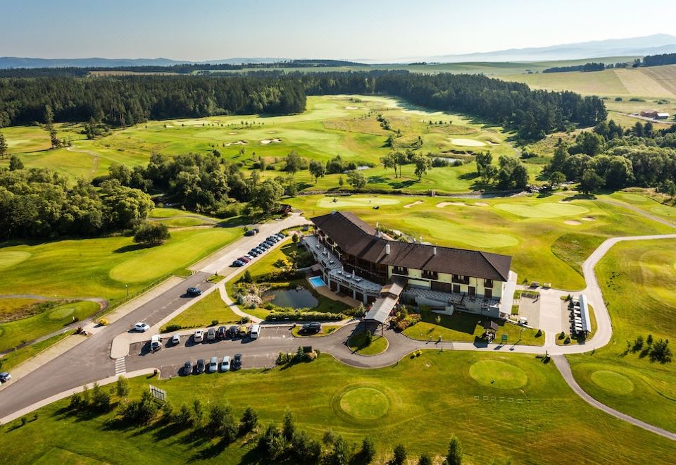 aerial view of a golf course with a large building and several cars parked on the grass at Hotel International