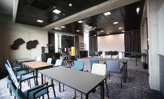 a large room with multiple tables and chairs arranged for a meeting or conference , with a projector screen on the wall at Arte Hotel Salzburg