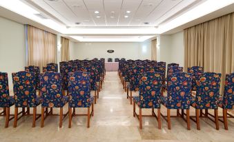 a large conference room with rows of blue floral chairs arranged in an orderly fashion at Elba Castillo San Jorge & Antigua Suite Hotel