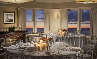 a large dining room with multiple tables set for a formal dinner , each table having its own unique arrangement of candle and glassware at Nantasket Beach Resort