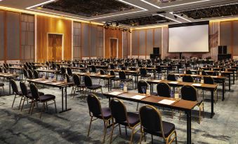 a large conference room with rows of chairs and tables , a projector screen at the front , and a wooden ceiling at Movenpick Resort Cam Ranh