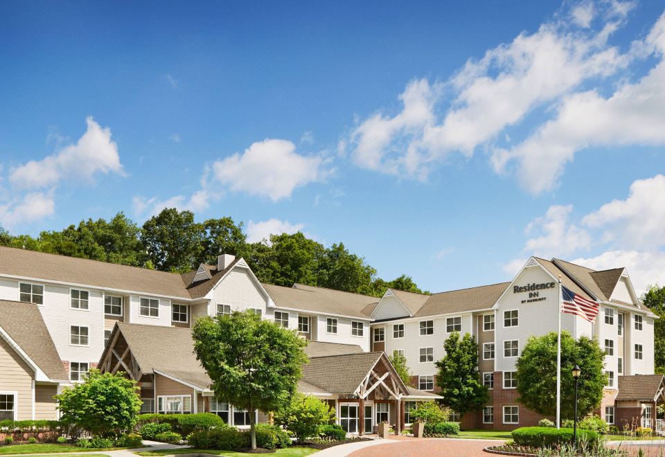 a large hotel with a green lawn in front of it and trees surrounding the area at Residence Inn Philadelphia Langhorne