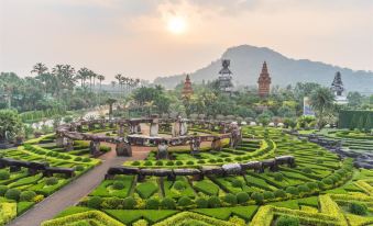 a scenic garden with winding paths and a large stone structure in the center , surrounded by lush greenery at Baan Tah on the Sea