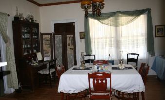 a dining room with a table set for four people , surrounded by chairs and a piano at Lamplight Inn