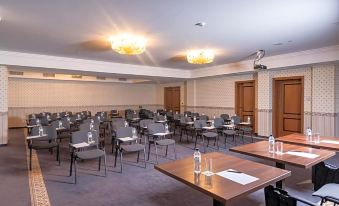 a conference room with rows of chairs and tables , water bottles on the tables , and chandeliers hanging from the ceiling at Festa Winter Palace Hotel