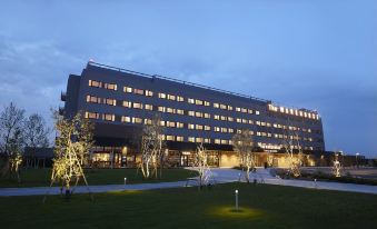 a large building with many windows and trees in front of it , illuminated by lights at Kawasaki King Skyfront Tokyu Rei Hotel