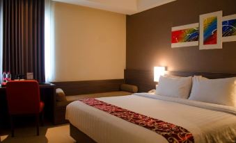 a well - lit hotel room with a bed , couch , and window , along with artwork on the wall at Hotel Horison Gkb Gresik