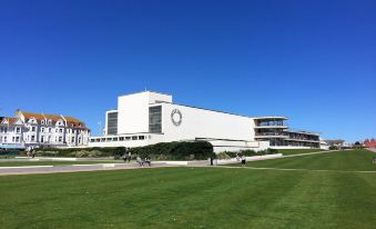 a large white building surrounded by a grassy field , with people walking on the grassy area at BexLet