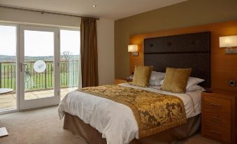a large bed with a brown headboard and gold linens is in a room with a sliding glass door at Hundith Hill Hotel
