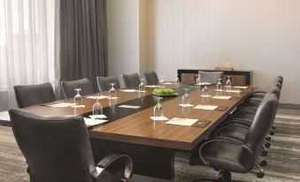 a conference room with a wooden table surrounded by chairs , and wine glasses on the table at DoubleTree by Hilton Cedar Rapids Convention Complex