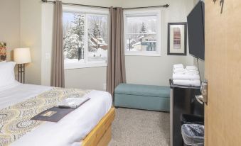 a cozy bedroom with a bed , window seat , and television , decorated for the winter season at Ski Inn