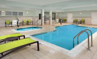 a large indoor swimming pool with multiple chairs and lounge chairs around it , creating a relaxing atmosphere at SpringHill Suites Alexandria