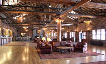 a large wooden lodge with multiple couches , chairs , and a fireplace , giving it a cozy and rustic atmosphere at Lake Lodge