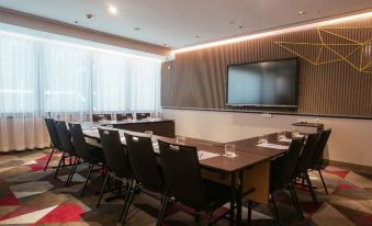 a conference room with a long table , chairs , and a television mounted on the wall at Capri by Fraser Brisbane