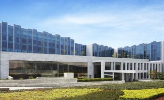 a modern building with large windows and a modern architectural design , surrounded by greenery and blue sky at Taj Bangalore